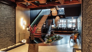A modern lobby with a staircase, wooden ceiling beams, and a reception desk. - Dom u ozera  (Burabay)