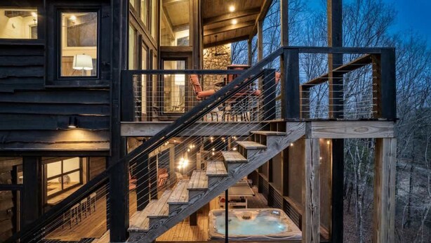 Eine mehrstöckige Holzhütte mit einer Treppe, die zu einem Whirlpoolbereich führt.