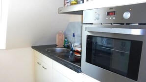 A modern kitchen with stainless steel appliances, a digital clock, and a built-in oven. - Holiday home in Thale in the Harz Mountains (Thale ot Allrode)