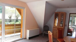 A room with a sliding glass door leading to a balcony, a radiator, a cabinet with glass doors, a chair, and a small table. - Holiday home in Thale in the Harz Mountains (Thale ot Allrode)