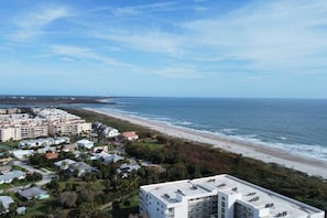 Un hôtel situé sur la côte, composé de plusieurs bâtiments, avec une plage et une vue sur l’océan.