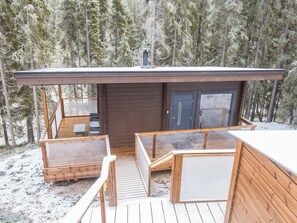 A wooden cabin with a deck, a small table, and a bench. - Villa ukkometso by Interhome (Kuusamo)