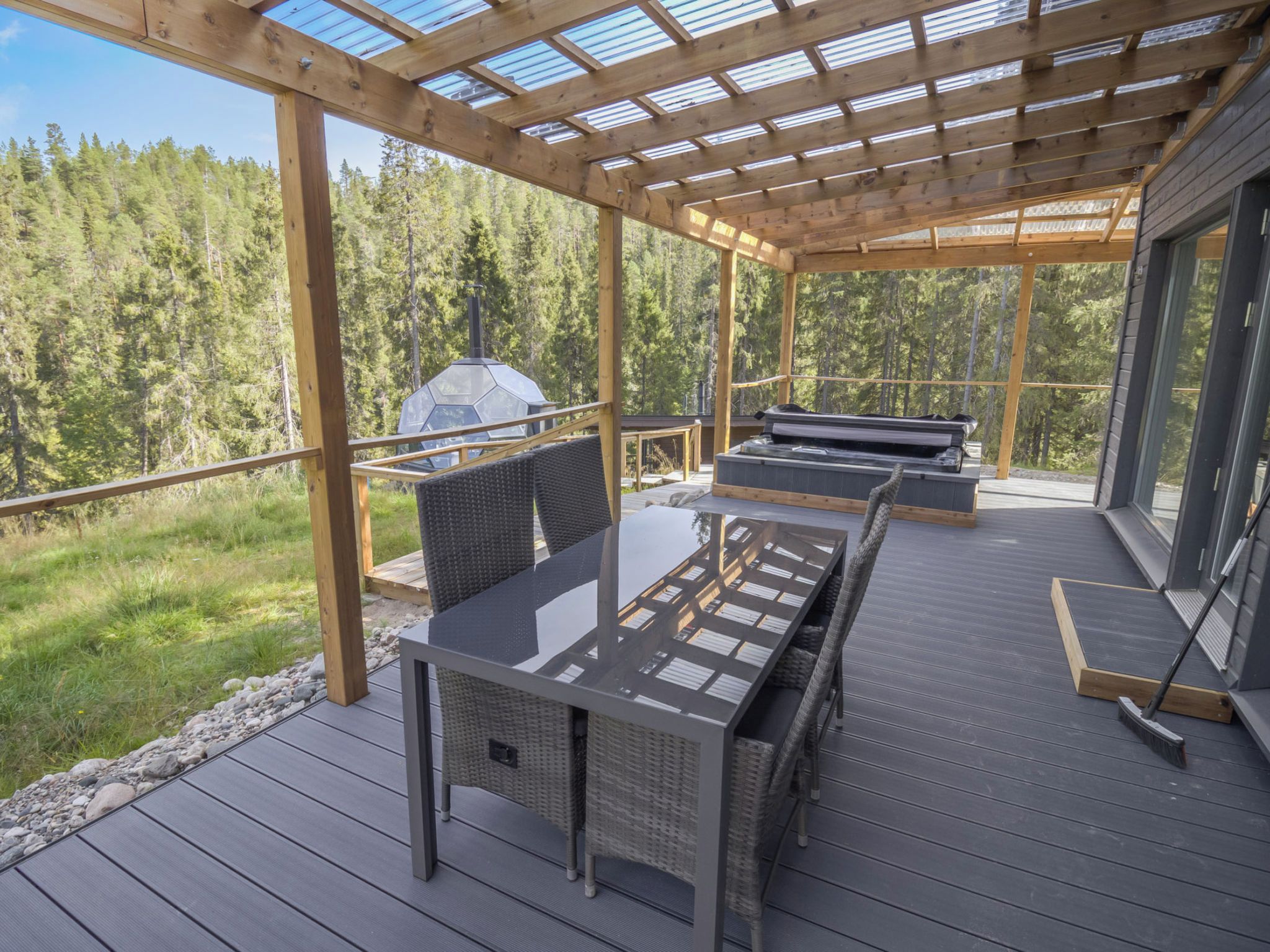 Eine Terrasse im Freien mit Pergola, Sitzgelegenheit und Grill.