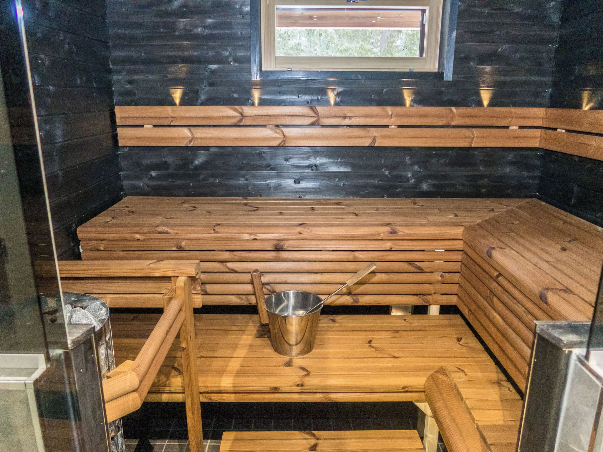 Uma sauna com bancos de madeira e um balde de metal.