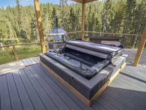 A hot tub on a wooden deck with a view of a forest.