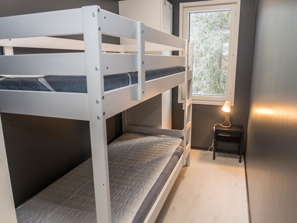 A bunk bed room with a window and a bedside table with a lamp.
