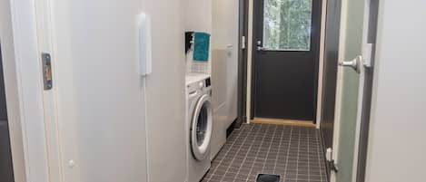 Ein Waschraum mit Waschmaschine, Handtuchhalter und einer Tür zu einem Raum mit einem Fenster.