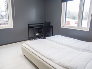 A bedroom with a bed, a desk, and a chair.
