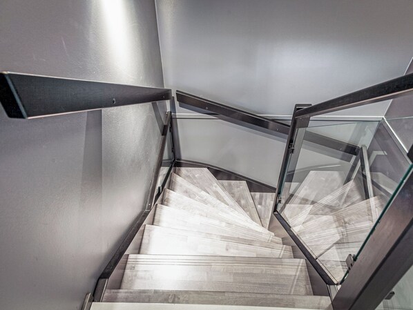 A modern staircase with glass railings and wooden steps.