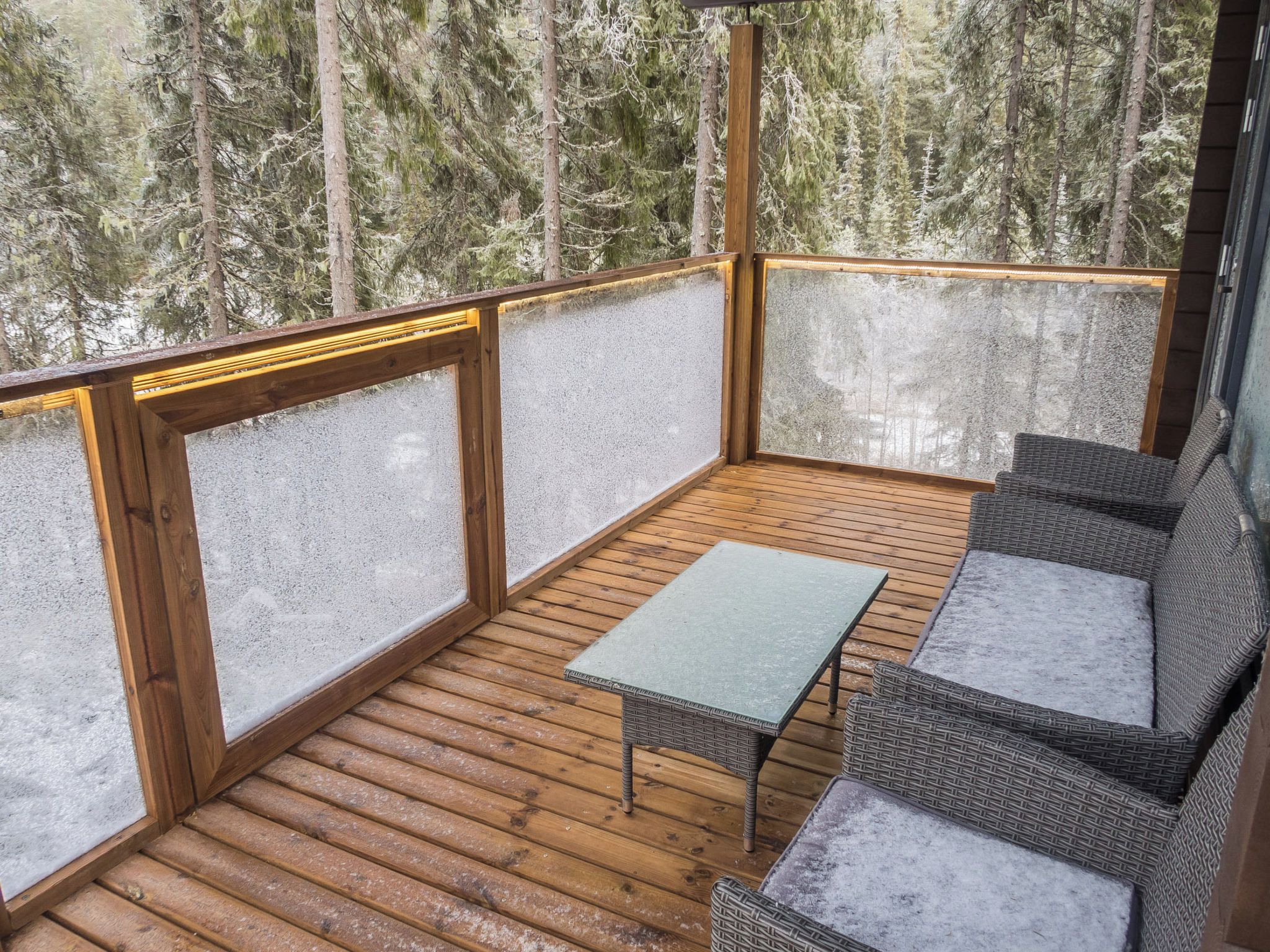 Eine überdachte Terrasse mit Tisch und Korbmöbeln.