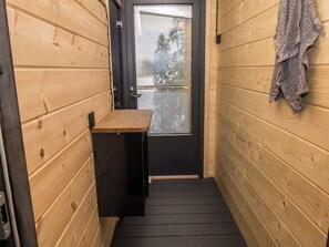 A narrow hallway with wooden walls, a black door, and a small wooden bench.