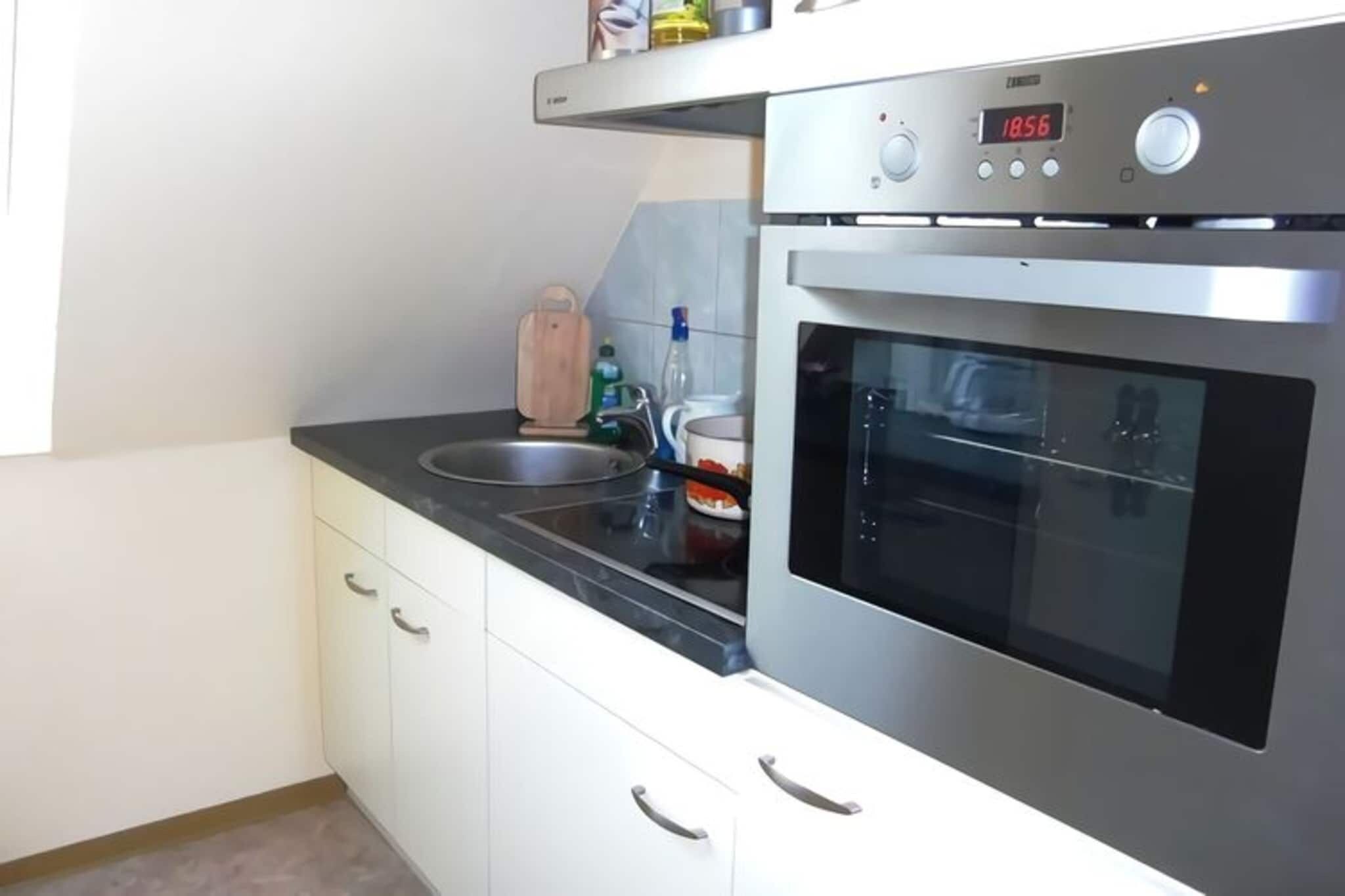 Eine moderne Küche mit Backofen aus Edelstahl, einer digitalen Uhr und einer integrierten Spüle.