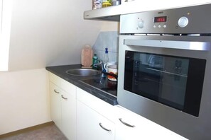 A modern kitchen with a stainless steel oven, a digital clock, and a built-in sink.