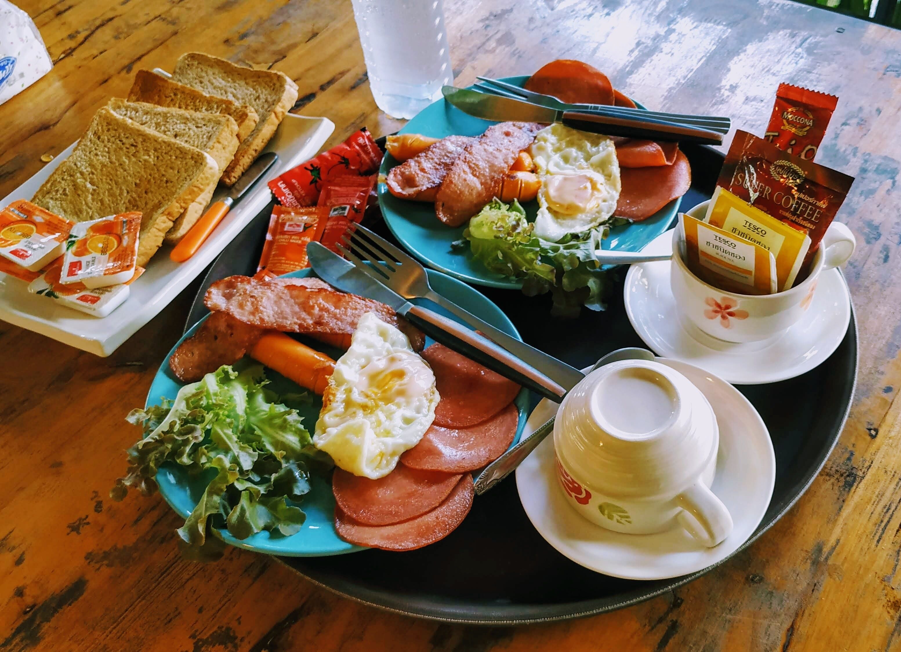 Un safata de petitdejuni amb torrades, ous, pernil i verdures damunt d'una taula de fusta.