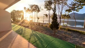 A view from a balcony overlooking a lake with trees and a distant mountain range. - Lake Camp Resort (Phipun)