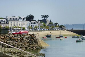 A coastal area with a stone jetty, boats, and a row of buildings with varied architecture. - House in Locquirec near Sandy Beaches (Locquirec)