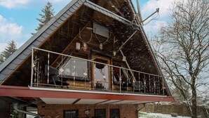 A modern house with a sloped roof, a balcony with a metal railing, and a chimney.