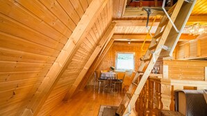 A wooden interior with a dining area, a staircase, and a window.