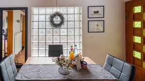 Ein Essbereich mit Tisch für zwei Personen, einem Fenster mit dekorativem Kranz und gerahmten Bildern an der Wand.