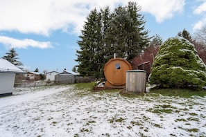 Cozy cabin with a unique barrel-shaped storage room, set amidst a serene forest landscape.