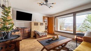 Ein modernes Wohnzimmer mit Couch, Fernseher an der Wand und einem Holztisch.