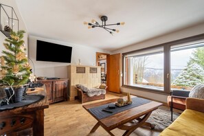 Relax in this inviting living room with a sofa, coffee table, and wall-mounted TV, offering a view of the outdoors.