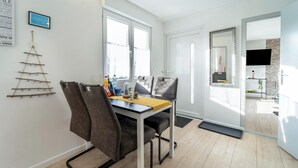 A modern dining area with a table, chairs, and a decorative tree on the wall.