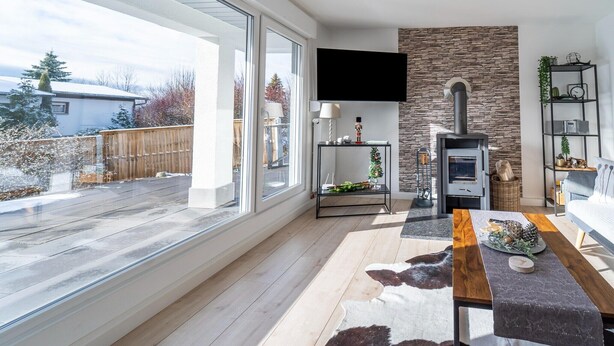 A modern living room with a fireplace, large windows, and a view of the outdoors.