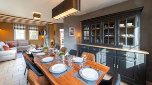 Un comedor moderno con una mesa de madera dispuesta para cuatro personas, flanqueada por sillas de cuero. A la derecha, un mueble de madera oscura con puertas de cristal.