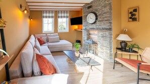 Una sala de estar con un sofá, una mesa de centro, una chimenea de piedra y un reloj en la pared.