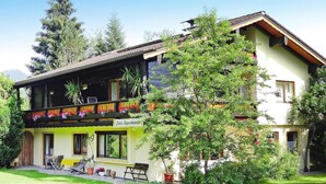 Un bâtiment à deux étages doté d’un balcon orné de fleurs, d’une enseigne indiquant « Restaurant éphémère de Jani » et d’un petit espace extérieur aménagé pour accueillir des clients.