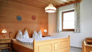 Une chambre à coucher aux murs lambrissés, avec un lit, deux tables de chevet dotées de lampes, une fenêtre avec des rideaux et des éléments de décoration murale.
