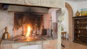Una chimenea con fuego, rodeada de objetos antiguos y una pared de ladrillo.