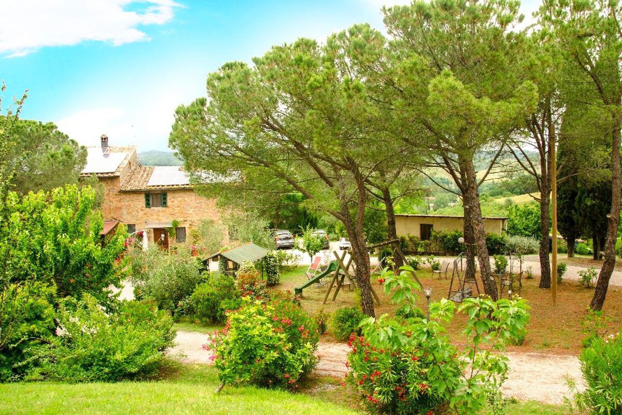 Une maison de campagne en pierre, dotée d’un jardin et entourée d’arbres et de verdure.