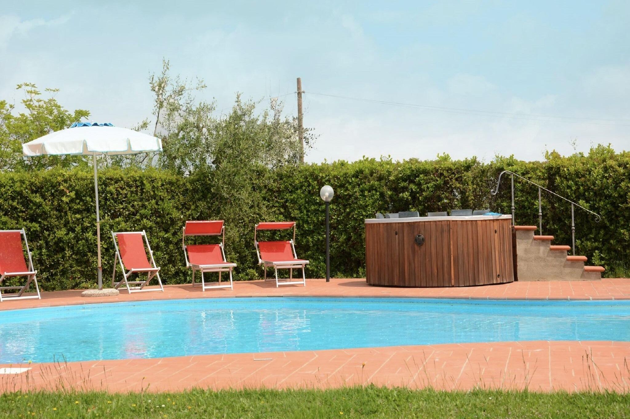 A swimming pool with lounge chairs and a hot tub.