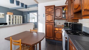 A modern kitchen with wooden cabinets, a dining table, and a stove. - Cosy cottage a stone's throw from Cap Gris Nez (Audinghen)