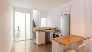 A modern kitchen with white cabinetry, a wooden countertop, and a built-in oven.