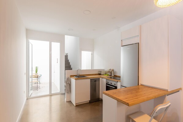 A modern kitchen with white cabinetry, a wooden countertop, and a built-in oven.