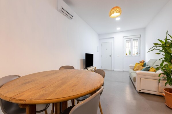 Una sala de estar moderna con una mesa de comedor de madera, un sofá y un televisor.