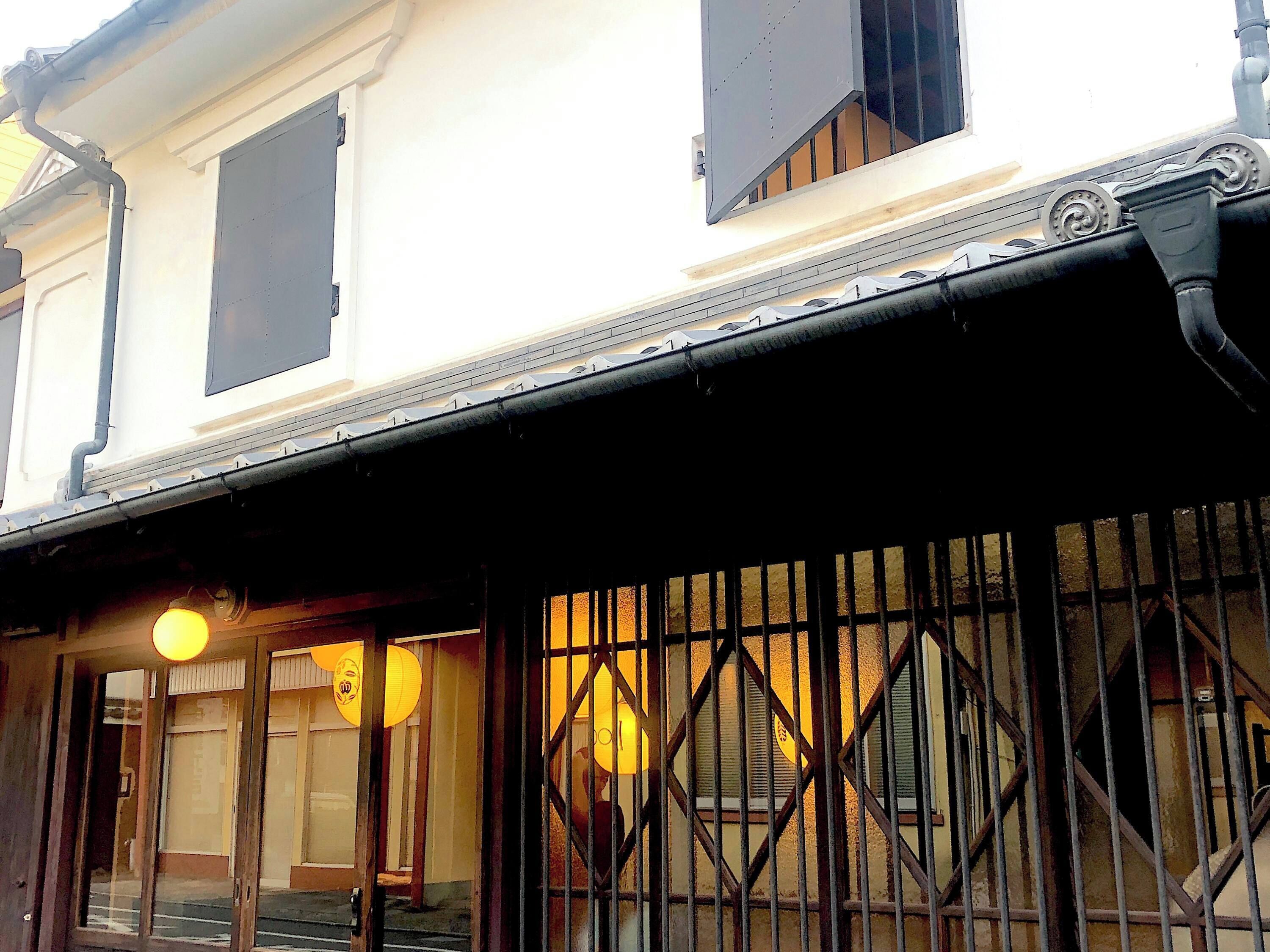 A building with a traditional architectural style, featuring a prominent entrance with a metal gate and a staircase leading to the upper floor.