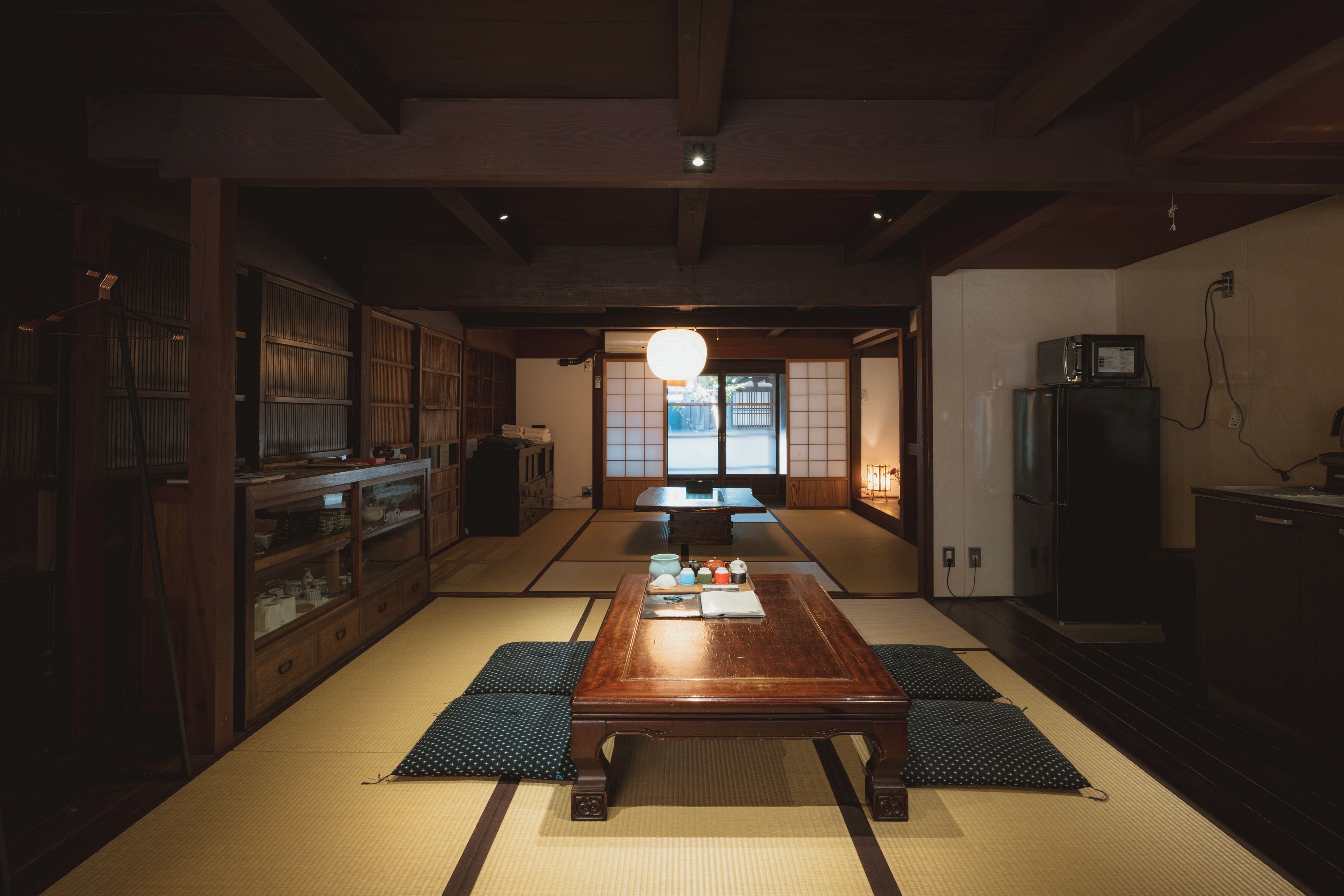 A traditional Japanese room with tatami flooring, a low wooden table, and a sliding door leading to a view outside.