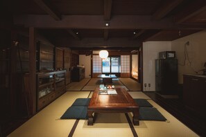 Una habitación japonesa tradicional con suelo de tatami, una mesa de madera baja y un fusuma que da a una vista exterior.