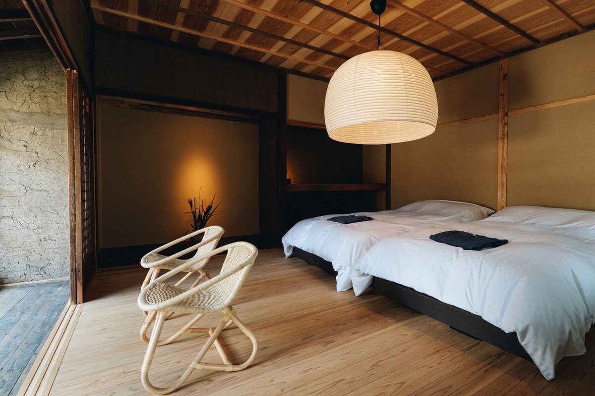 Una camera da letto con un letto, una sedia e una lampada a sospensione.