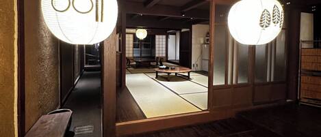 A traditional Japanese room with tatami flooring, a low wooden table, and two hanging paper lanterns.