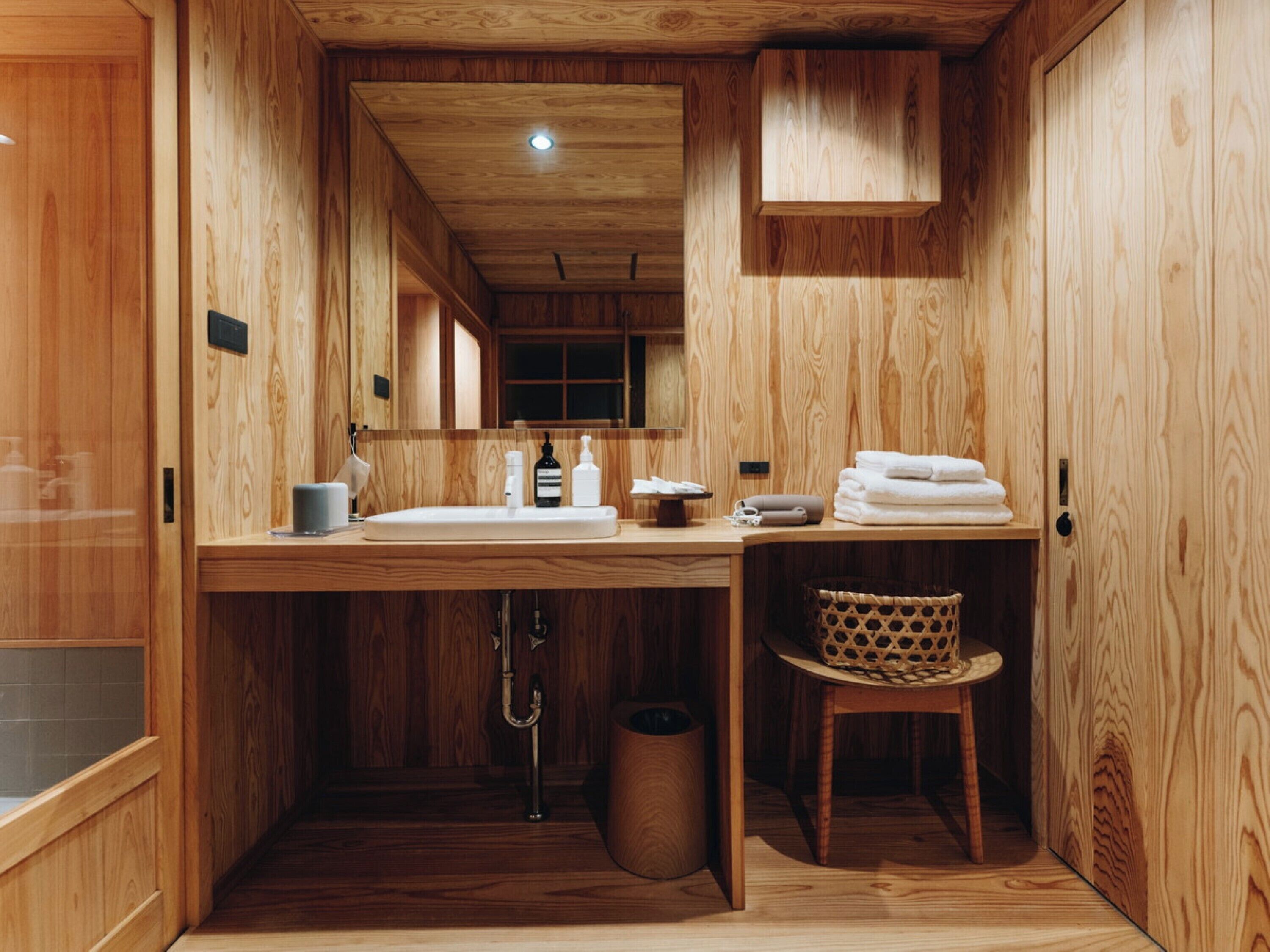 Un baño de madera con lavamanos, espejo y toallero.
