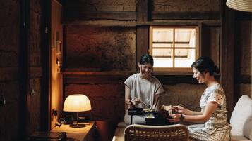A cozy room with a wooden interior, a table with a lamp, and two people dining.