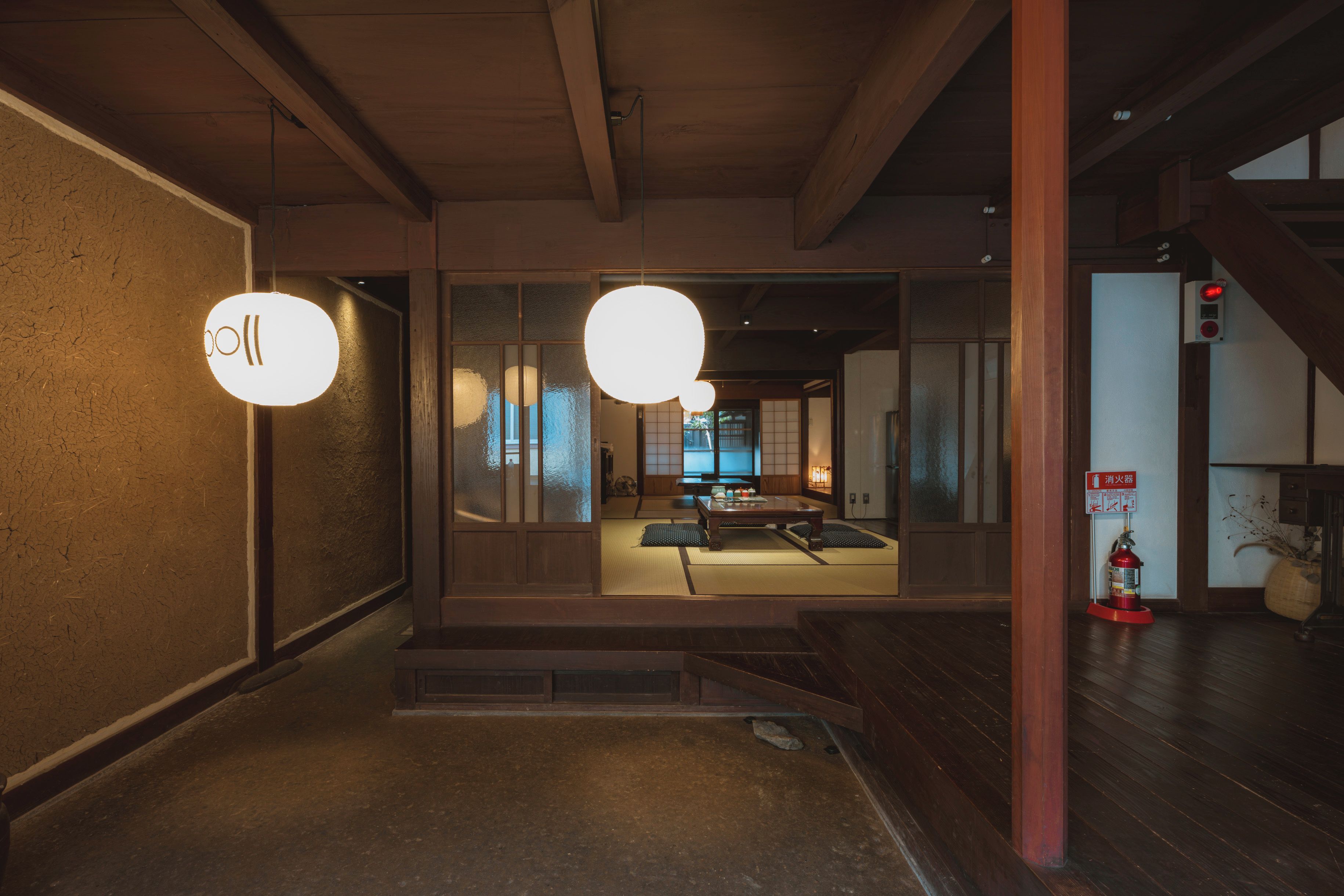 A traditional interior with tatami flooring, a low wooden table, and a hanging light fixture.