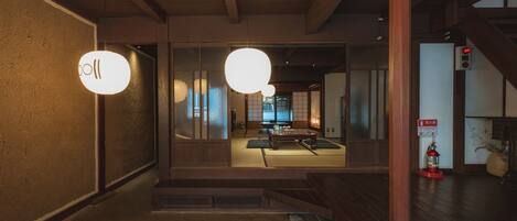 A traditional interior with tatami flooring, a low wooden table, and a hanging light fixture.