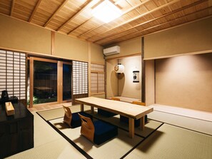 A traditional Japanese room with tatami flooring, a low table, and sliding doors.