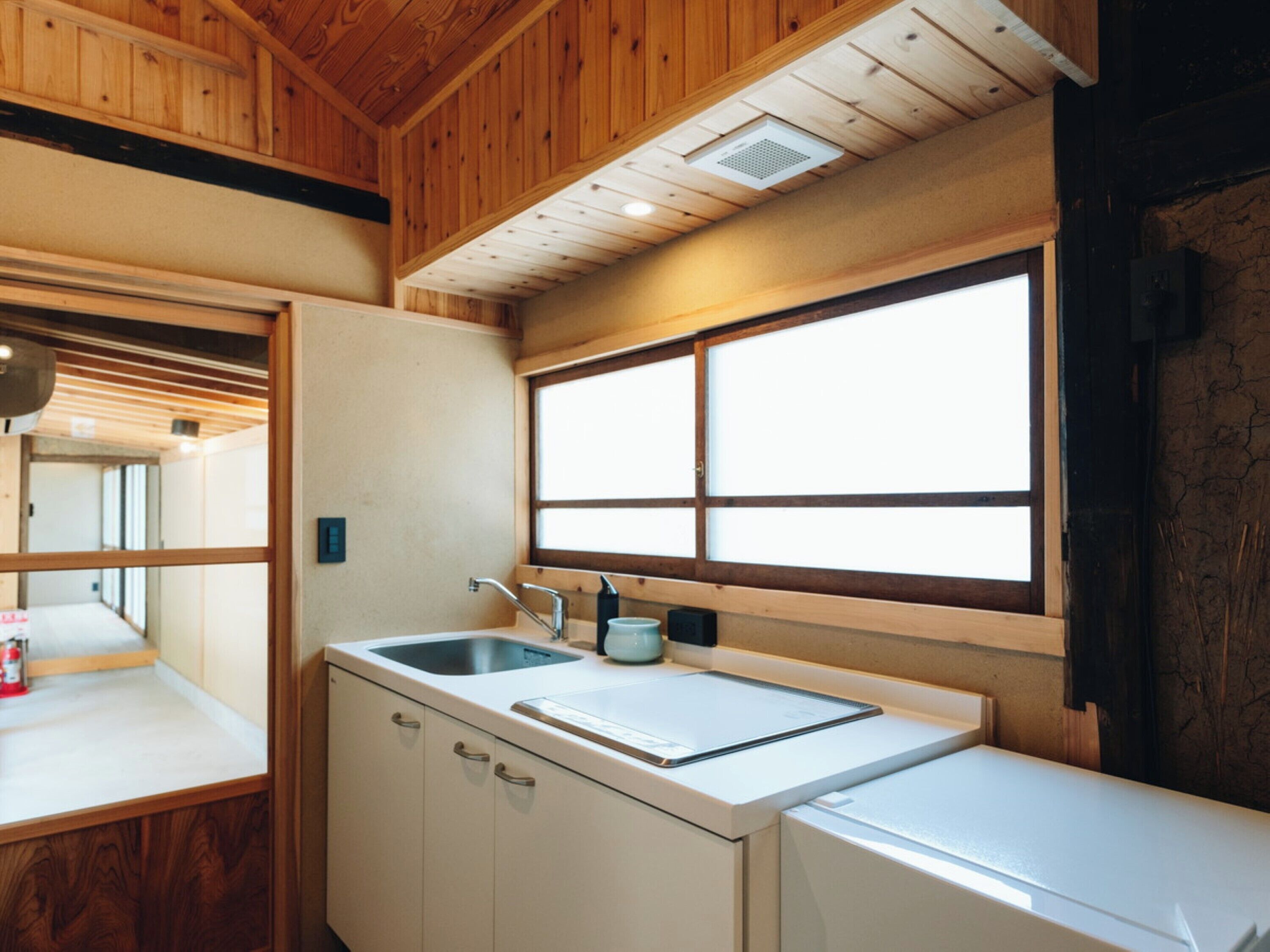 A compact kitchen with a sink, a window, and wooden ceiling beams.